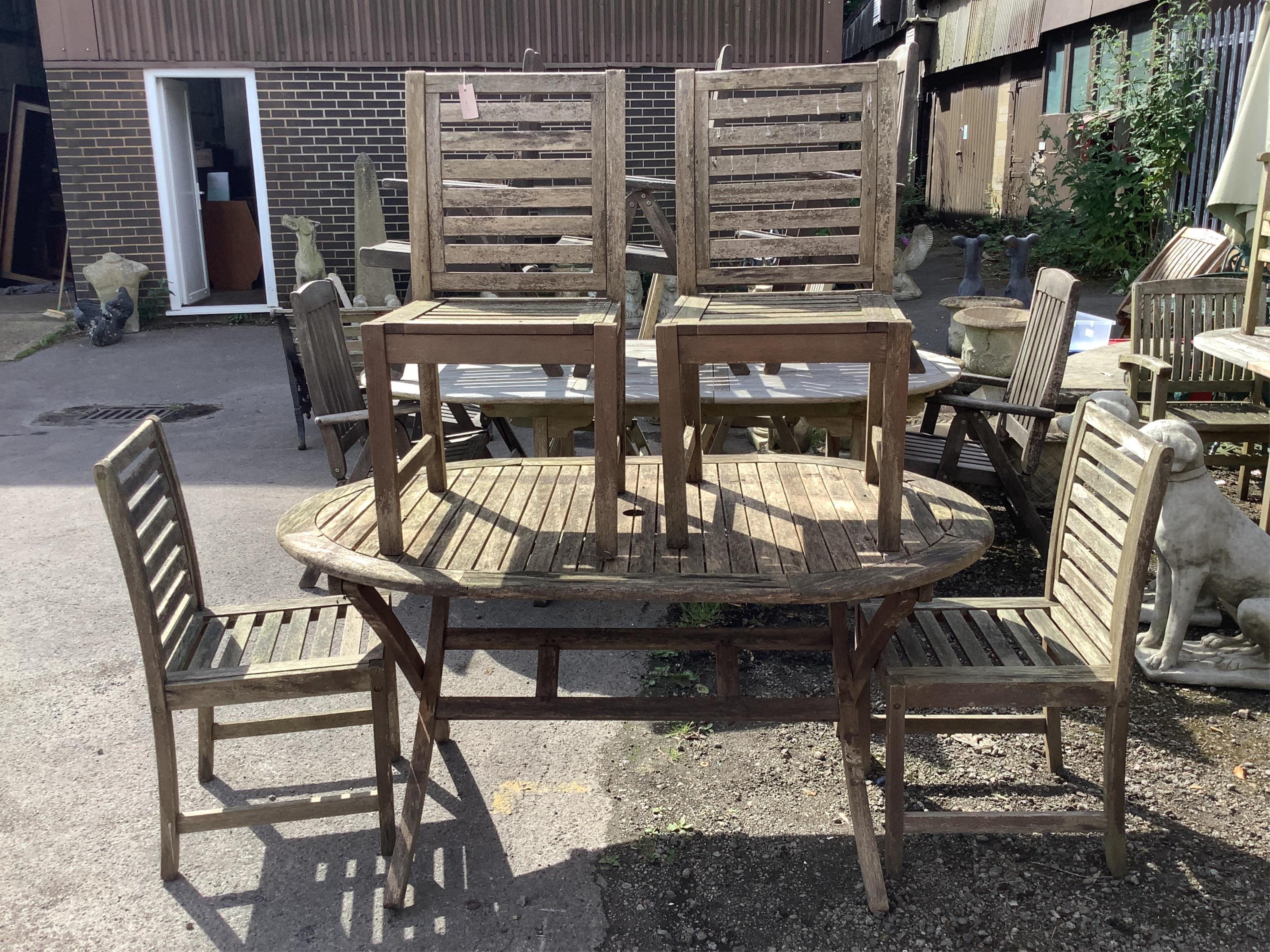 A weathered teak folding garden table, width 150cm, depth 90cm, height 71cm and four chairs. Condition - fair